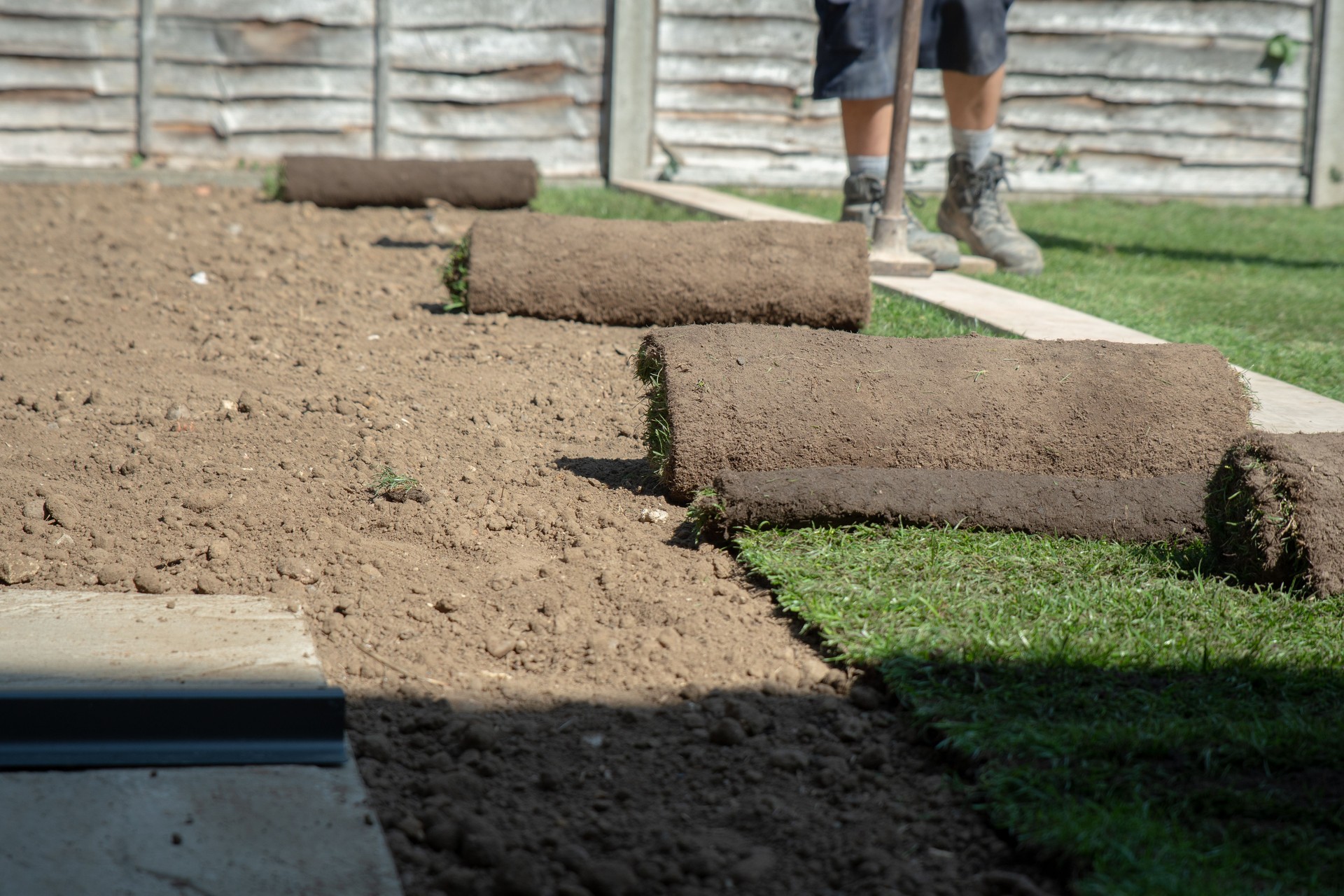 New turf being laid out in the back garden of a home in England.